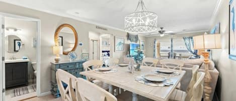 A spacious dining area with a large table, multiple chairs, and a decorative chandelier.