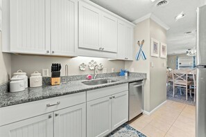 A kitchen with white cabinets, a granite countertop, and a stainless steel sink. - Channel Marker D2- 2 BR Beach Across The Street (North Myrtle Beach)