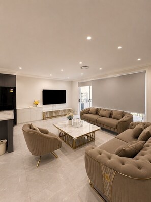 Uma sala de estar moderna com sofá, mesa de centro e televisão de tela plana na parede.