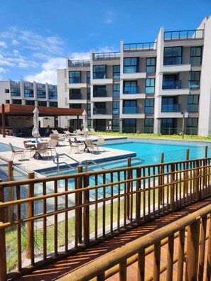 A modern hotel with a swimming pool, outdoor seating, and a view of the building's exterior. - F1.302 | Exclusive penthouse with spa in Carneiros! (Tamandaré)