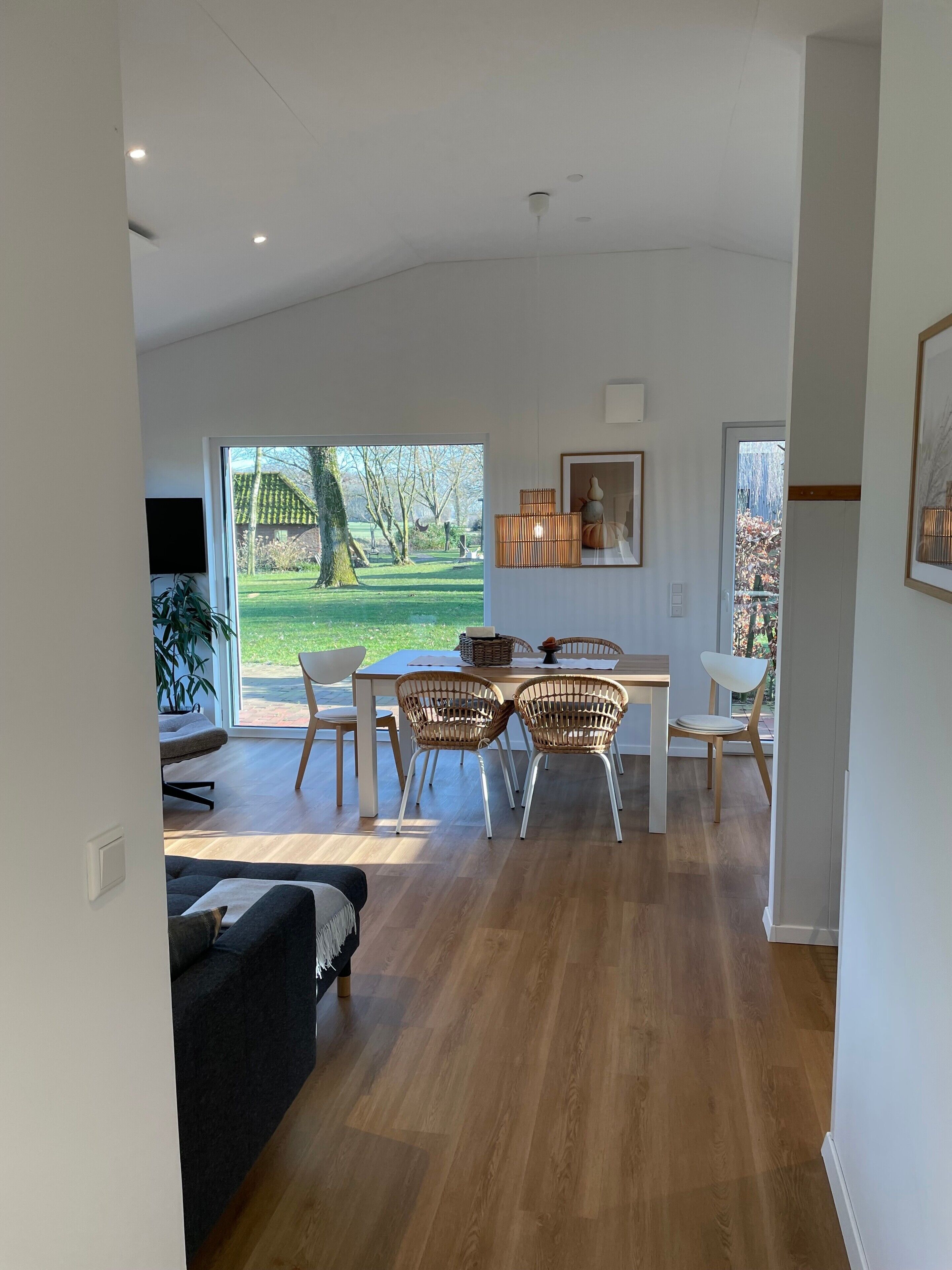 Ein modernes Interieur mit Essbereich, einer Couch und Blick auf einen Garten.