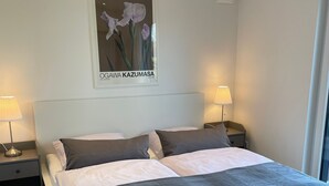 Une chambre moderne avec un grand lit, deux tables de chevet avec des lampes, un tableau accroché au mur et un plancher en bois.
