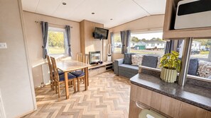 Un espacio habitable compacto con comedor, asientos, televisor y ventana con vistas.