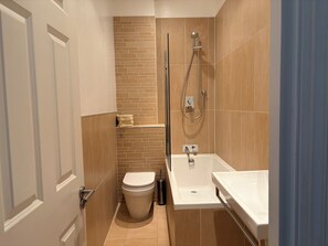 Une petite salle de bain comprenant des toilettes, une douche et un lavabo.