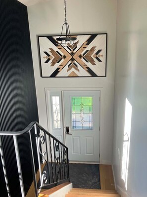 A staircase leading to a door with a geometric wall art piece above it. - Lovstrom Estates - Beautiful Private Countryside retreat (NESBITT)