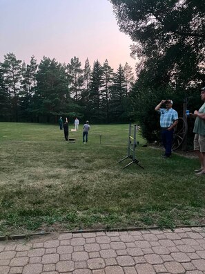 A grassy outdoor area with a paved walkway, trees, and a group of people. - Lovstrom Estates - Beautiful Private Countryside retreat (NESBITT)