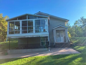 A two-story house with a large windowed upper floor and a smaller entrance with steps. - Lovstrom Estates - Beautiful Private Countryside retreat (NESBITT)