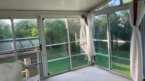 A covered patio with a view of a green lawn and trees.