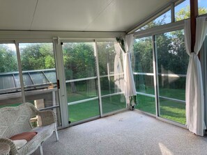 A covered patio with a view of a green lawn and trees.