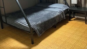 A bunk bed with a desk and curtains in a room with a patterned floor.