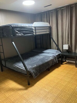 A bunk bed with a desk and curtains in a room with a patterned floor.