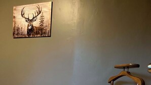 A room with a grey wall, a wooden floor, and a wooden coat rack.
