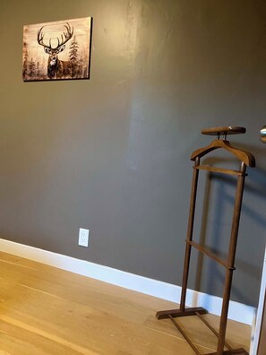 A room with a grey wall, a wooden floor, and a wooden coat rack.