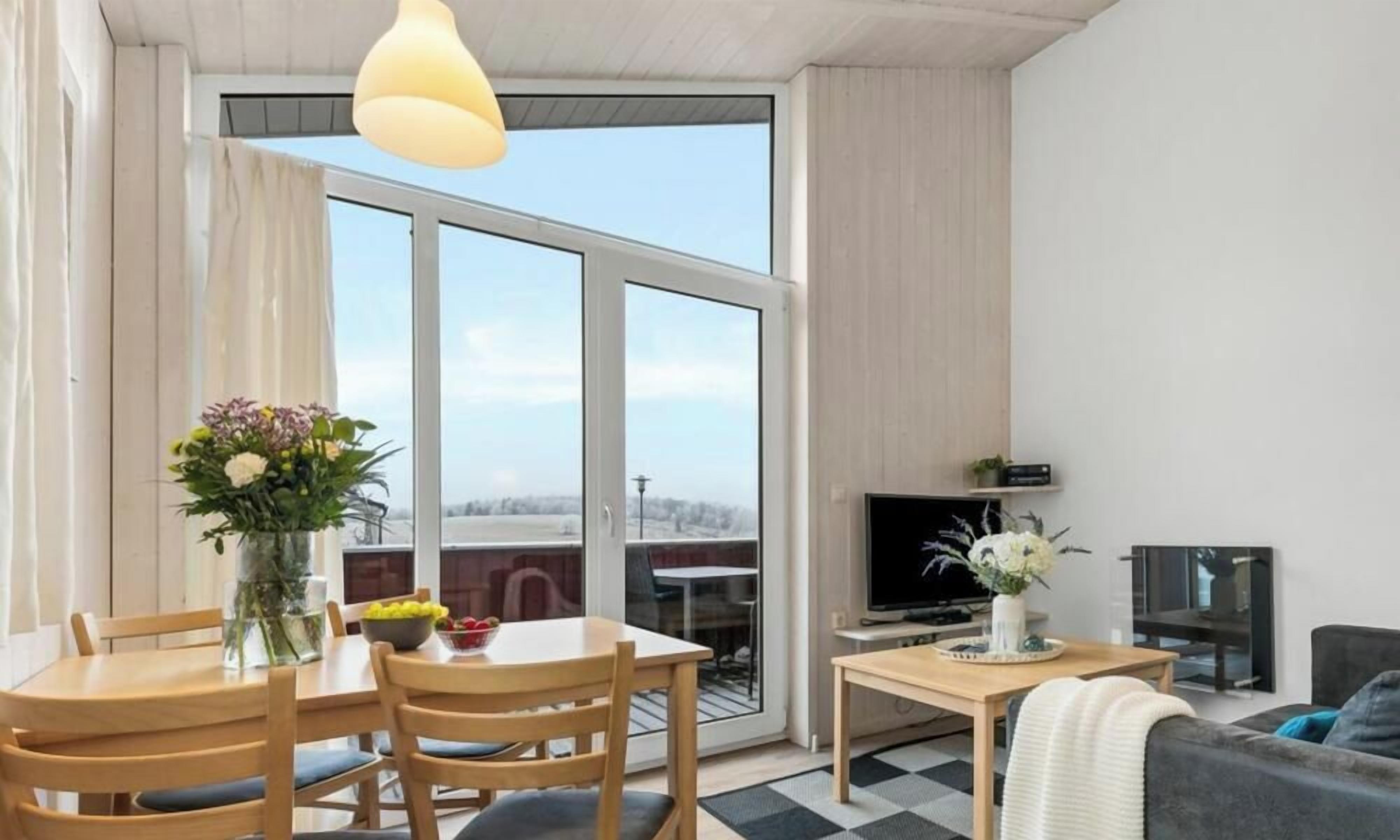 En moderne stue med spiseområde, store vinduer, et fladskærms-tv og en sofa.