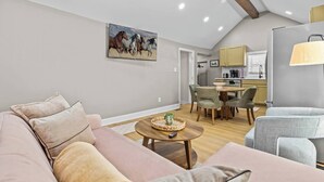En moderne stue med sofa, spisebord og et køkken i baggrunden.