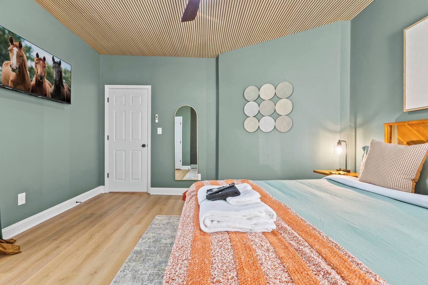 Una camera da letto con un letto, un comodino, una lampada, uno specchio e un'opera d'arte appesa al muro.