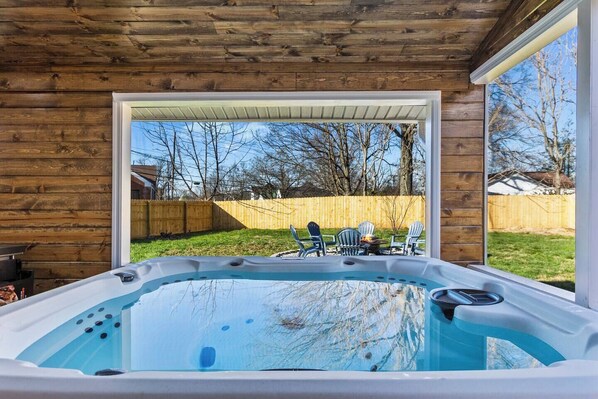 Un jacuzzi con vista a un patio trasero y una valla de madera.