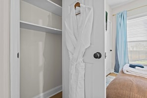 Una habitació amb un armari blanc, un llit amb una colcha marró i una finestra amb cortines blaves.