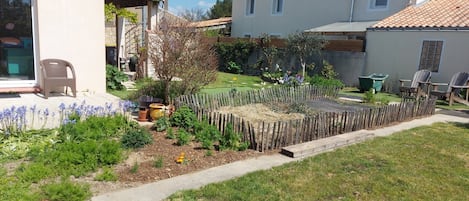 A garden with a wooden fence, potted plants, and a patio area with outdoor furniture.