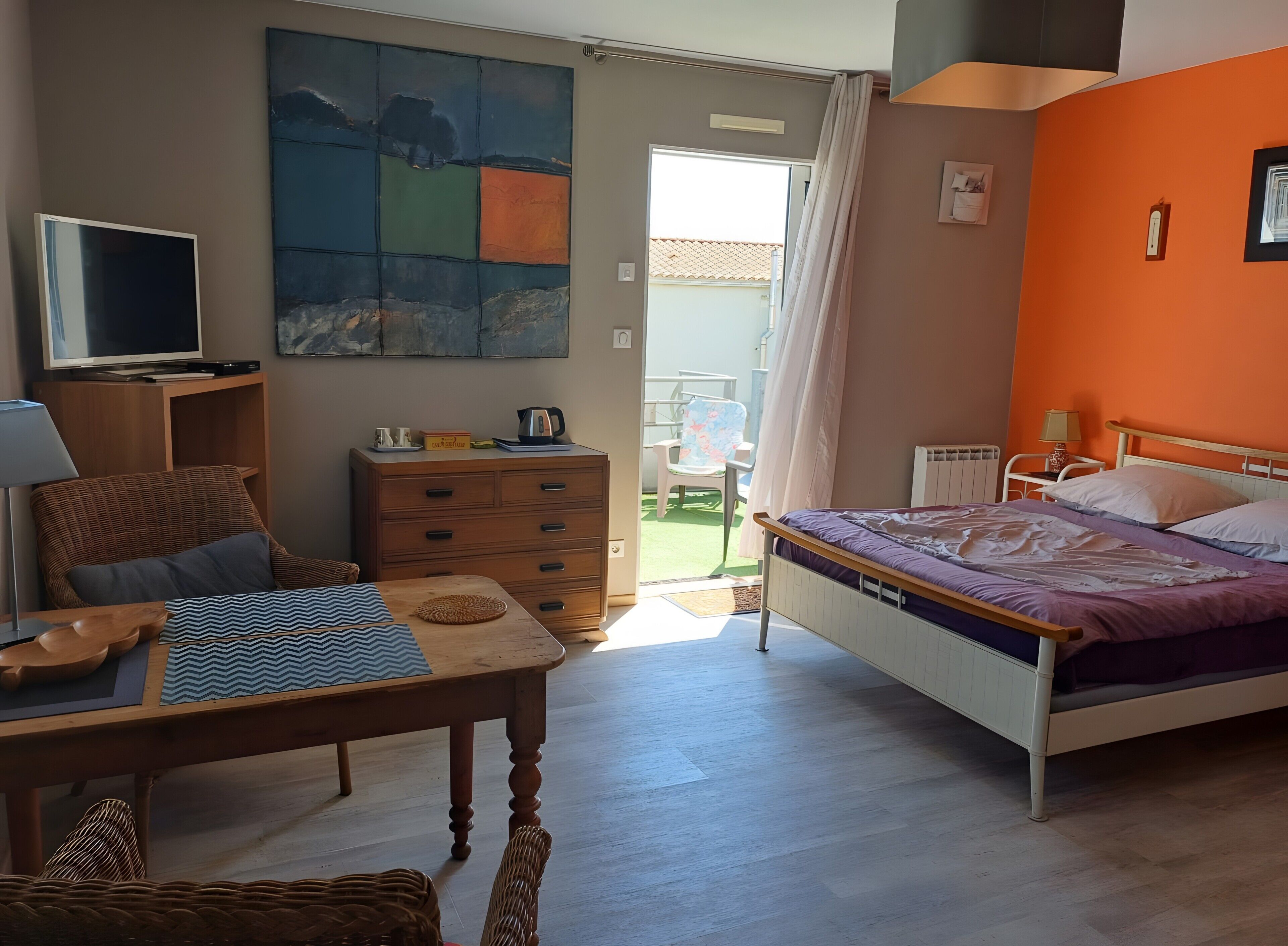 Une chambre à coucher avec un lit, un bureau, une chaise, une commode, un téléviseur et un tableau accroché au mur.