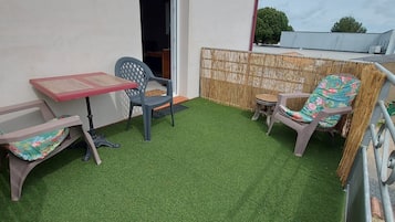 Een klein terras met een tafel en twee stoelen, een kleine ronde tafel en een decoratieve bamboescherm.