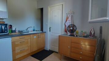 A compact kitchen with a microwave, sink, and wooden cabinets.