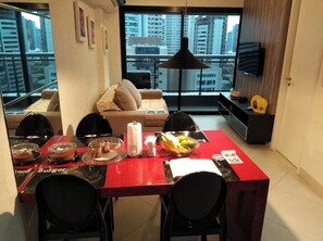 A dining area with a red table, black chairs, and a bowl of fruit. - Seaside landscape (Fortaleza)