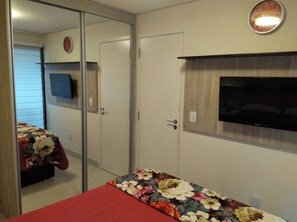 A bedroom with a bed, a wardrobe, a television, and a mirror. - Seaside landscape (Fortaleza)