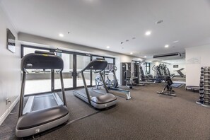 Ein Fitnessstudio mit Laufbändern, Krafttrainingsgeräten und einer Spiegelwand.