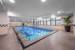 Ein Swimmingpool mit einer Fliesenbordüre, einer Leiter und einem Fenster mit Blick ins Freie.