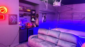 A room with a gaming setup including a couch, a pool table, and various gaming consoles and accessories. - Beautiful townhome near Celebration Point and UF Shands (Gainesville)