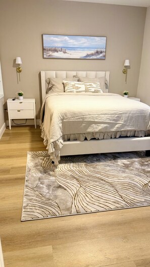 A bedroom with a bed, nightstands, a painting, and a patterned rug. - Beautiful townhome near Celebration Point and UF Shands (Gainesville)
