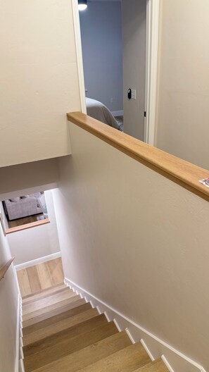A wooden staircase with white trim leading to a room with a bed. - Beautiful townhome near Celebration Point and UF Shands (Gainesville)
