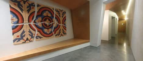 Un pasillo de diseño moderno, con una gran obra de arte abstracta en la pared y un banco de madera.