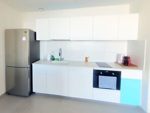 A modern kitchen with white cabinets, a stainless steel refrigerator, a sink, and a built-in oven. - Spacious New 1BD Balcony Mamad Levinski Florentin (Tel Aviv-Yafo)