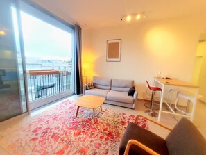 A modern living room with a sofa, a coffee table, and a dining area with a table and chairs. - Spacious New 1BD Balcony Mamad Levinski Florentin (Tel Aviv-Yafo)