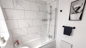 A modern bathroom with a glass shower enclosure, a white sink, and a towel rack. - The Cozy Home - Cozy 3 Bedroom House (Telford)