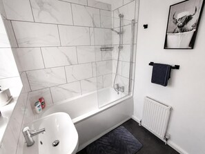 Une salle de bain moderne avec une douche à parois de verre, un lavabo blanc et un porte-serviettes.