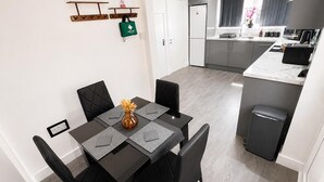 A modern kitchen with grey cabinets, a built-in oven, and a stainless steel refrigerator. - The Cozy Home - Cozy 3 Bedroom House (Telford)