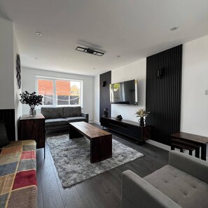 Un salon moderne avec un canapé, une table basse et un téléviseur placés contre un mur.