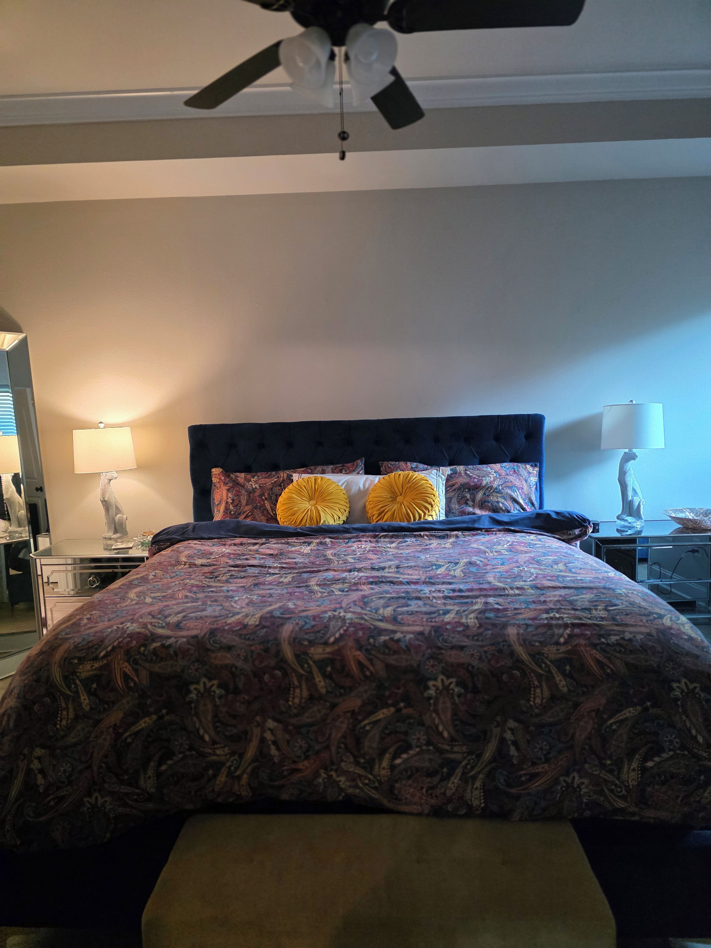 Una camera da letto con un letto, una ventola a soffitto e due lampade ai comodini.