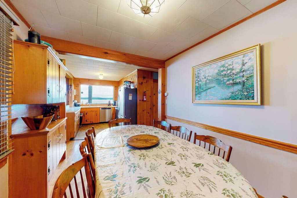 Un comedor con una mesa redonda, sillas de madera y un cuadro en la pared.