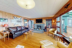 A cozy living room with a fireplace, leather sofa, and wooden flooring. - 5BR Lakefront Dog Friendly - Dock - Deck - Washer Dryer (Alton)