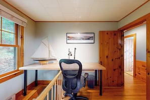 A room with a wooden desk, a black office chair, a small sailboat model, a desk lamp, and a framed picture on the wall. - 5BR Lakefront Dog Friendly - Dock - Deck - Washer Dryer (Alton)