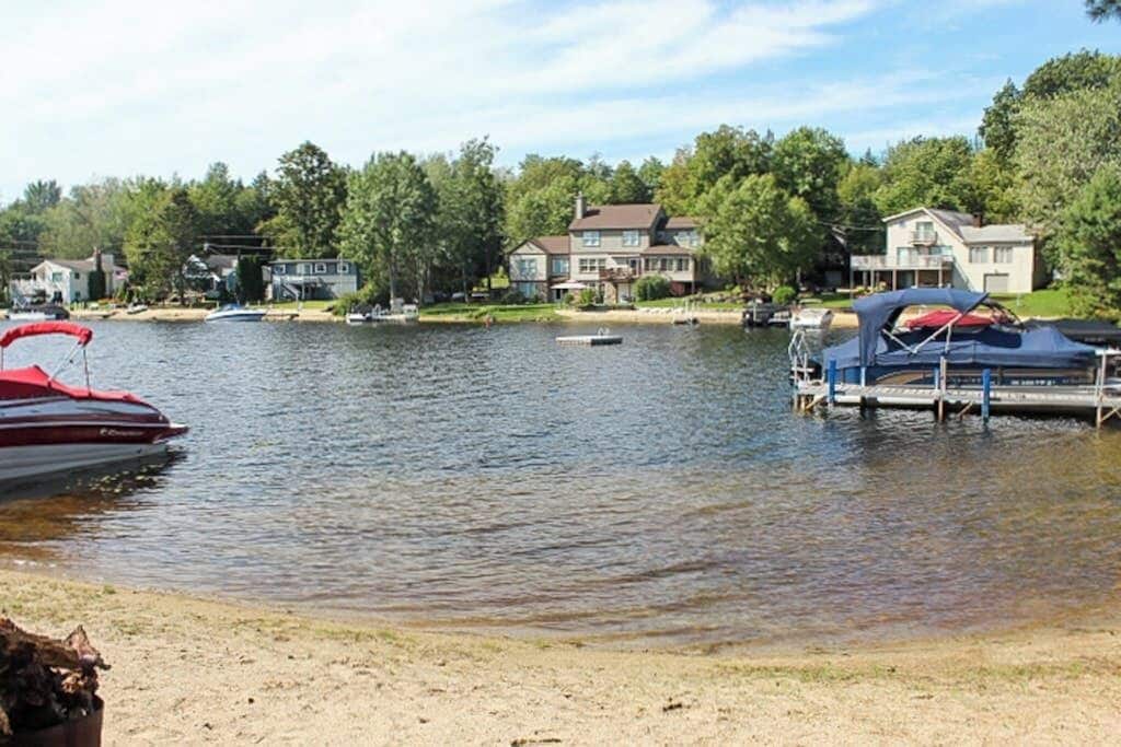 A lake with boats, a dock, and houses in the background.