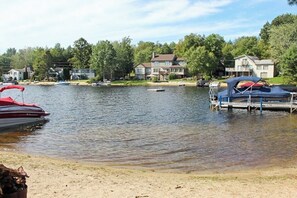 A lake with boats, a dock, and houses in the background. - Lakefront dog-friendly home with private beach (Moultonborough)