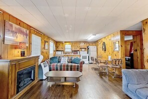 Ein Ferienhaus-Innenraum mit Kamin, einer Couch, einem Esstisch und einer Küchenzeile.