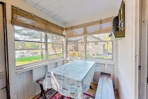 Ein Zimmer mit einem Tisch, der mit einer Tischdecke bedeckt ist, einer Bank und einem Fenster mit Jalousien.