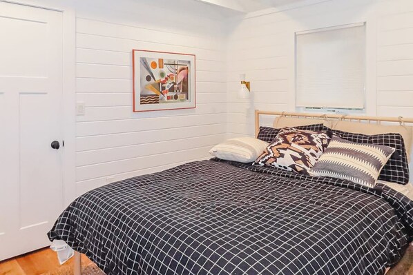 A bedroom with a bed, a wall-mounted picture, a window with blinds, and a door. - Updated 3BR Lakefront Dog Friendly - Washer Dryer (Moultonborough)