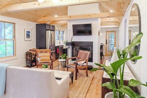 A cozy cabin interior with a fireplace, wooden furniture, and a kitchen area. - Updated 3BR Lakefront Dog Friendly - Washer Dryer (Moultonborough)